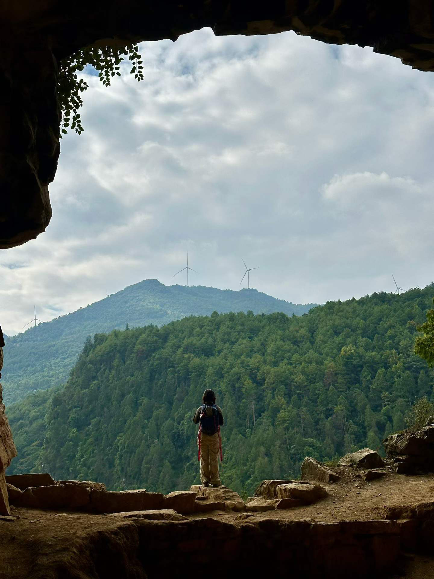 Hiker overlooking forested mountains and wind turbines near Chongqing