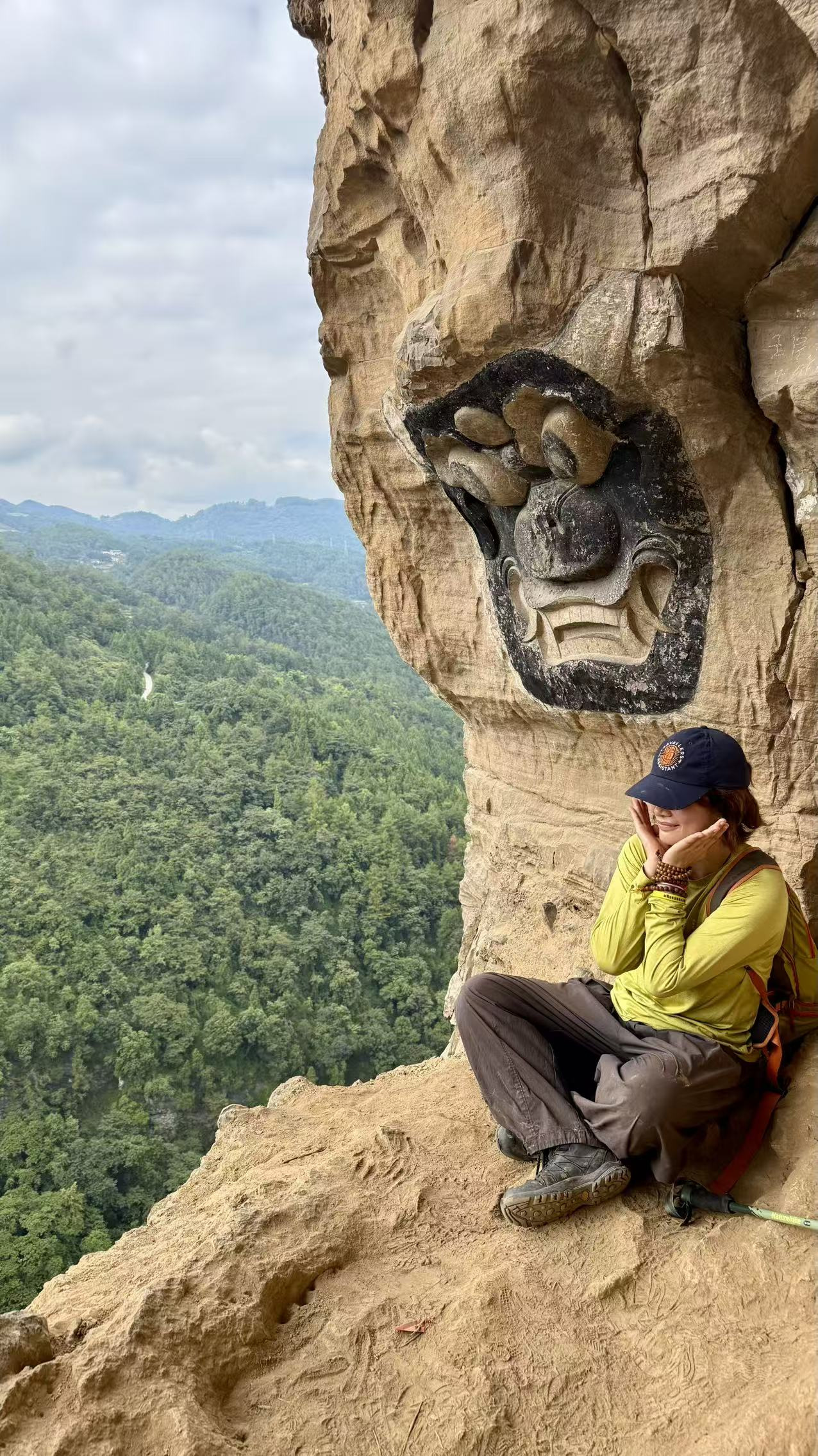Hiker beside a cliff carving above the forest